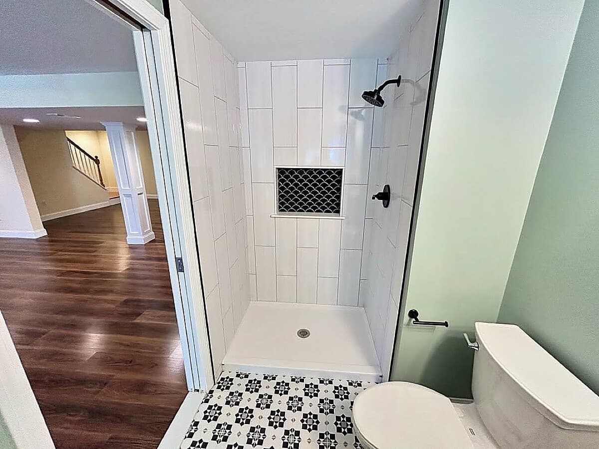 Basement bathroom with decorative tile shower and patterned floor