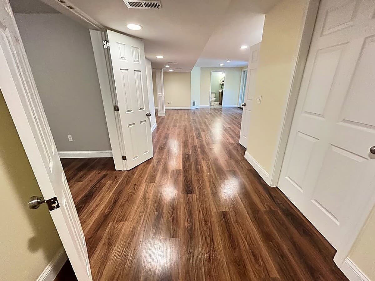 Finished basement hallway with hardwood floors and multiple rooms