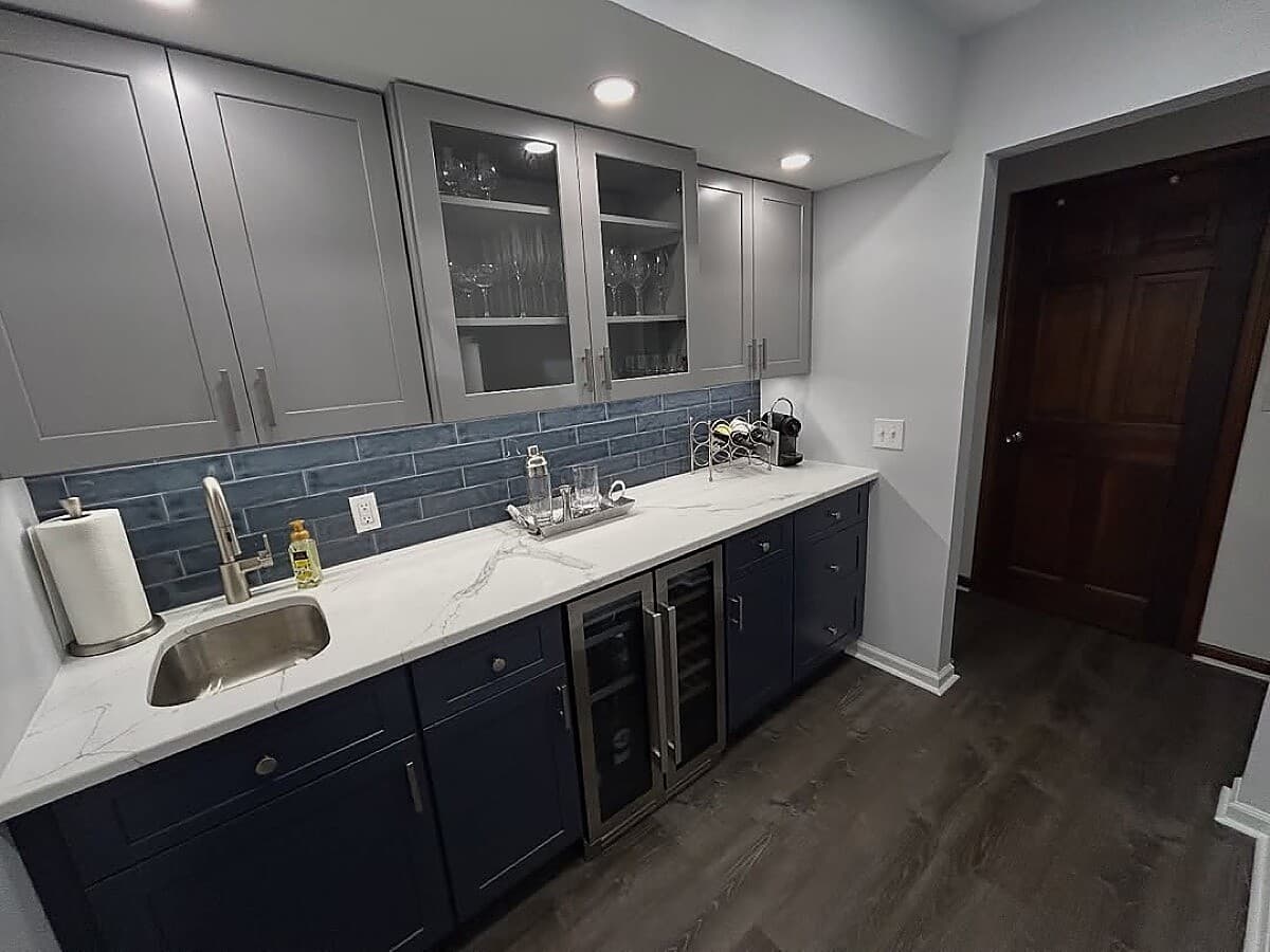 Basement wet bar with navy cabinets, blue tile backsplash, and wine fridge