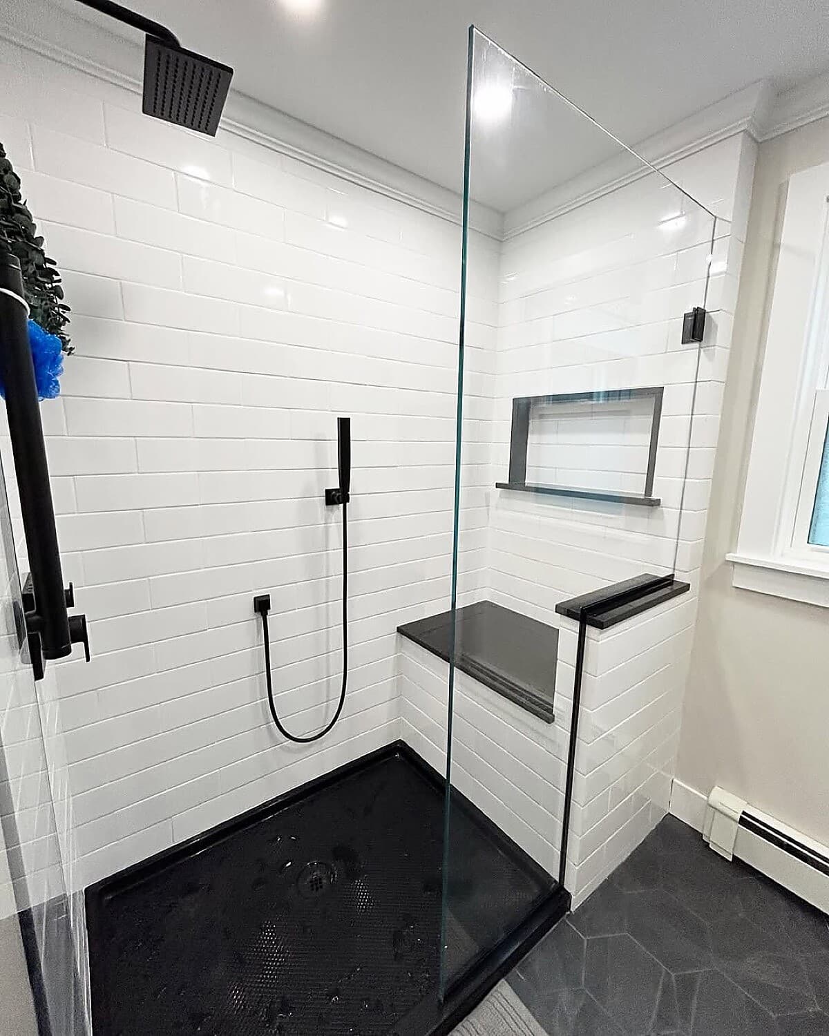 Walk-in shower with black fixtures, white subway tile, and niche shelving