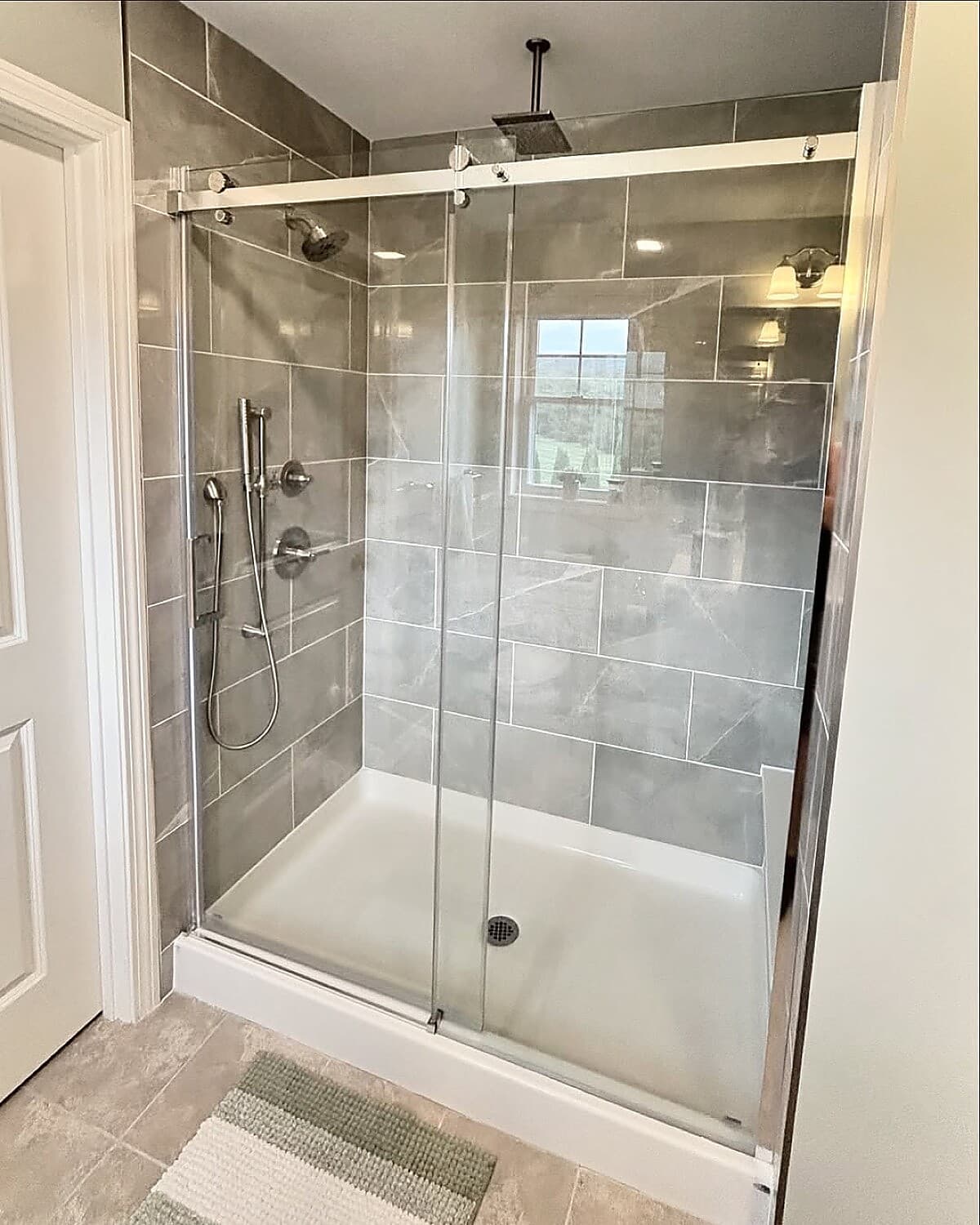 Frameless glass shower with rain head and decorative floor tile