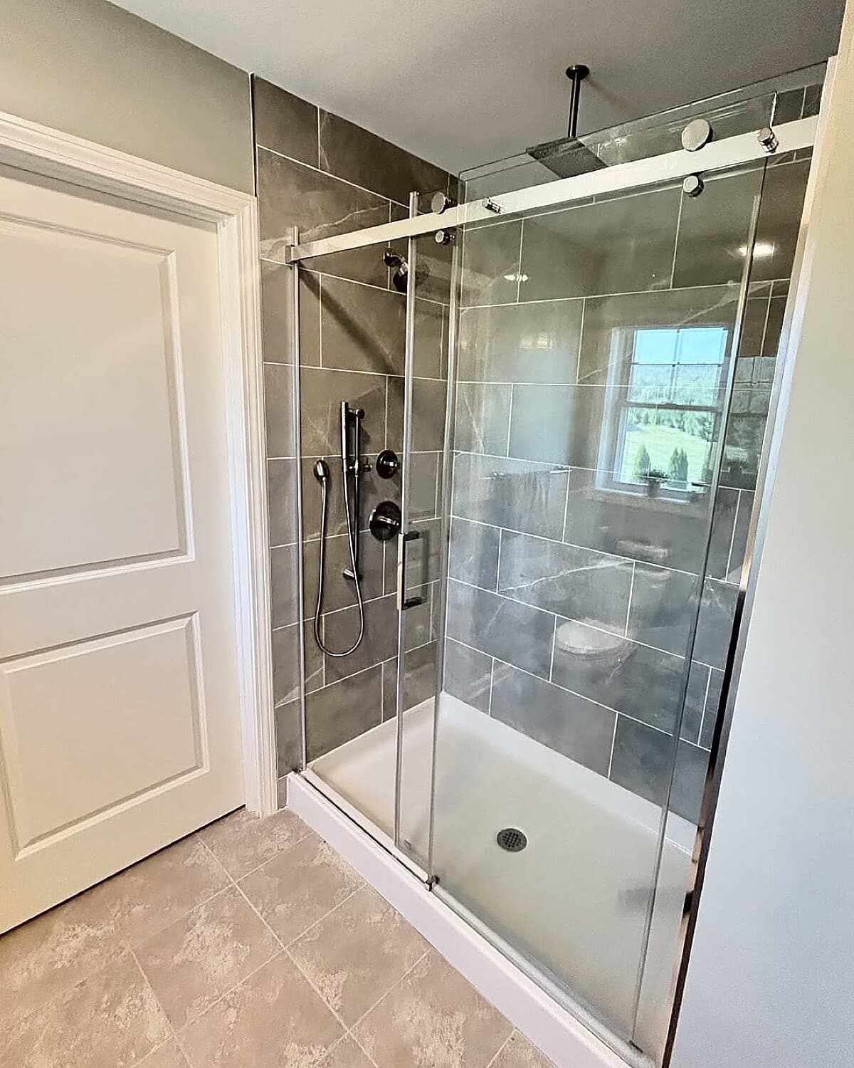 Gray marble walk-in shower with sliding glass door and rain head