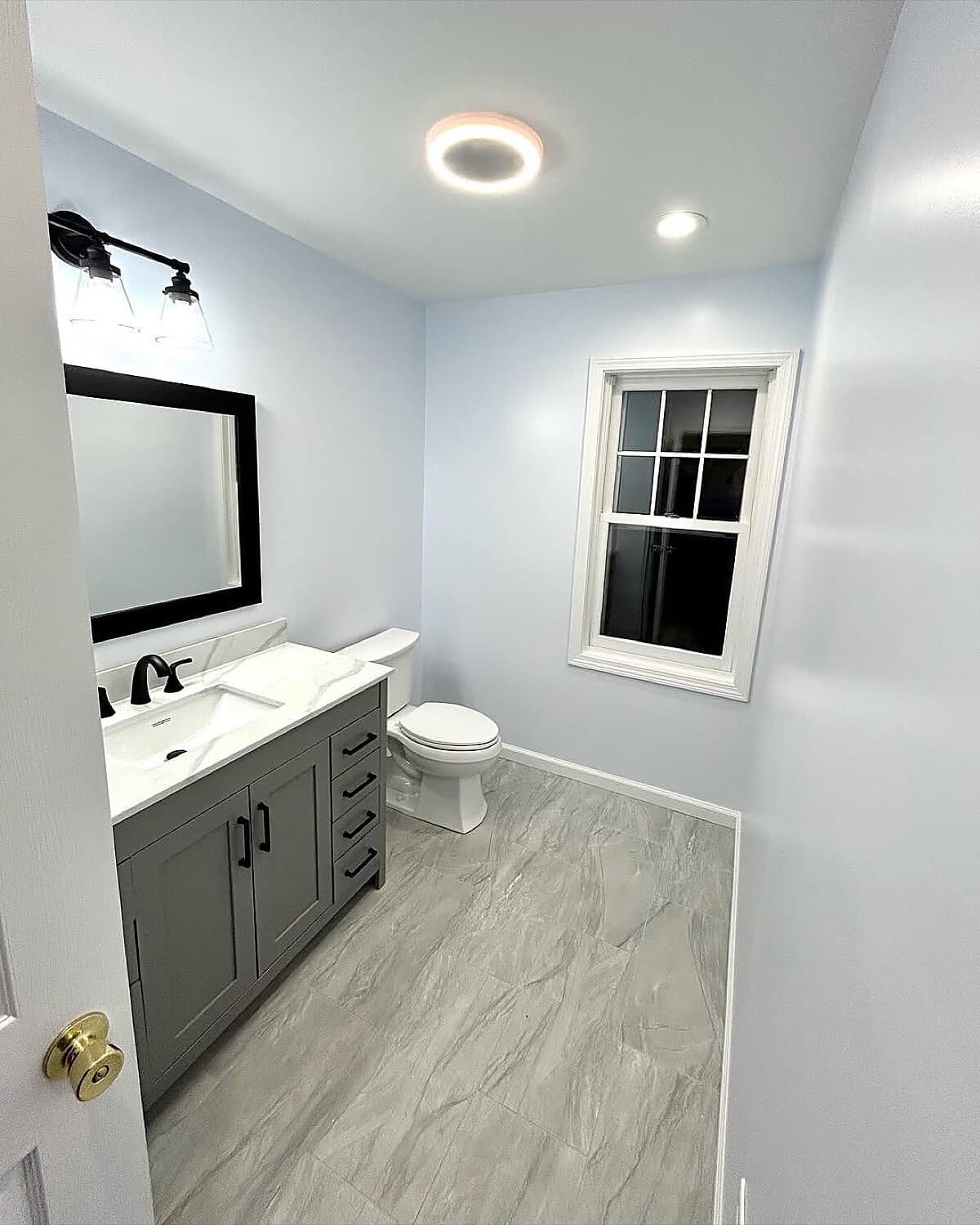 Bathroom with gray vanity, marble floor tile, and industrial lighting