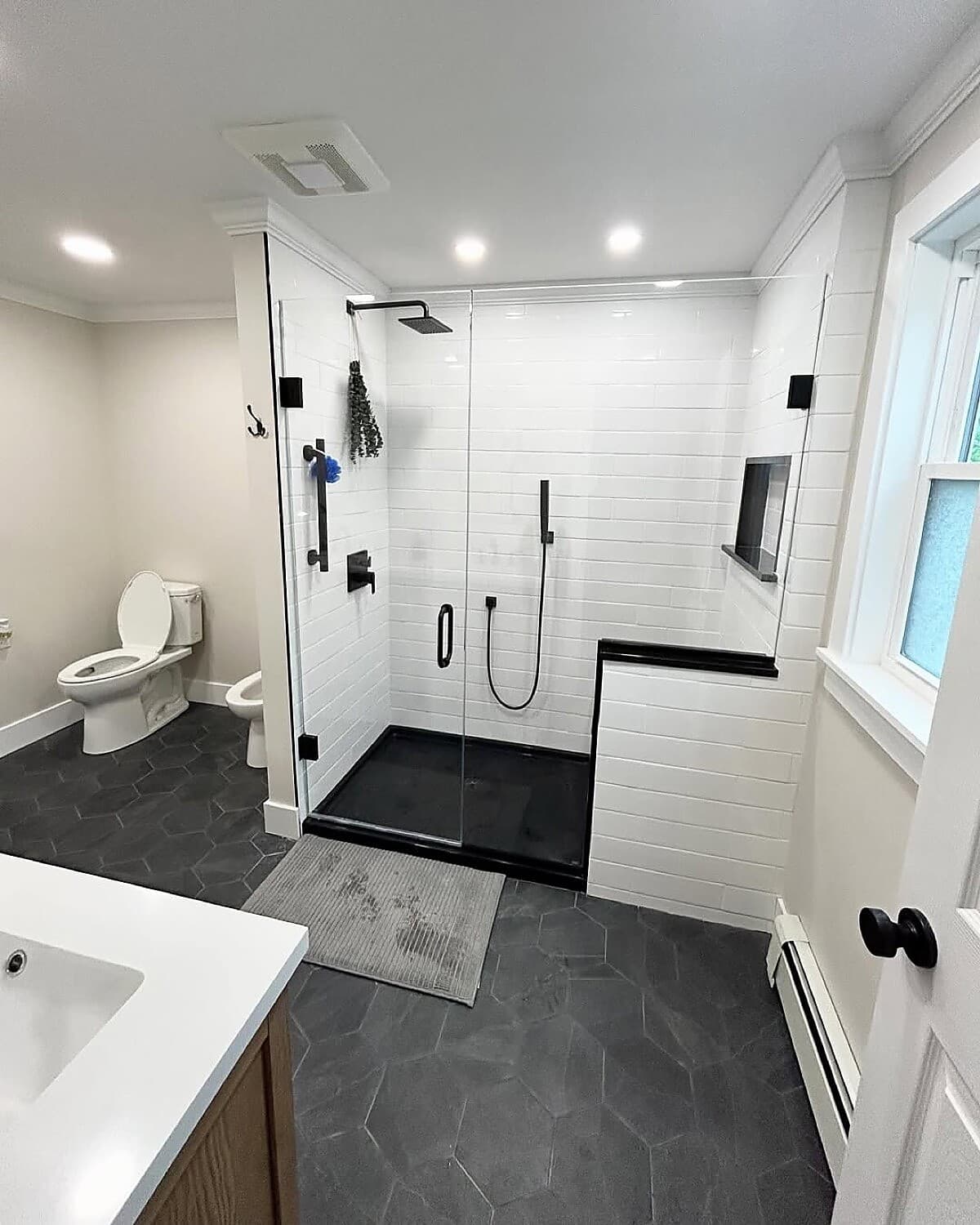 Modern bathroom with frameless glass shower and dark hexagon floor tile