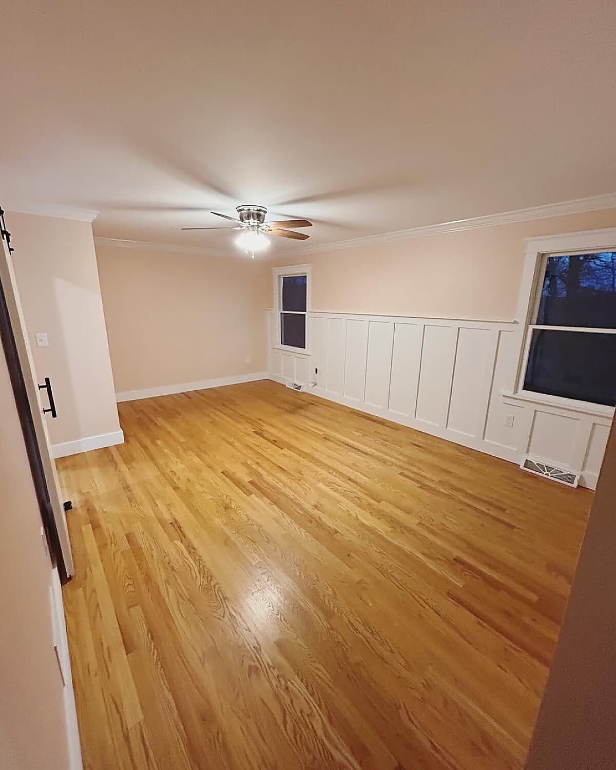 Living room with hardwood floors, white wainscoting, and barn door